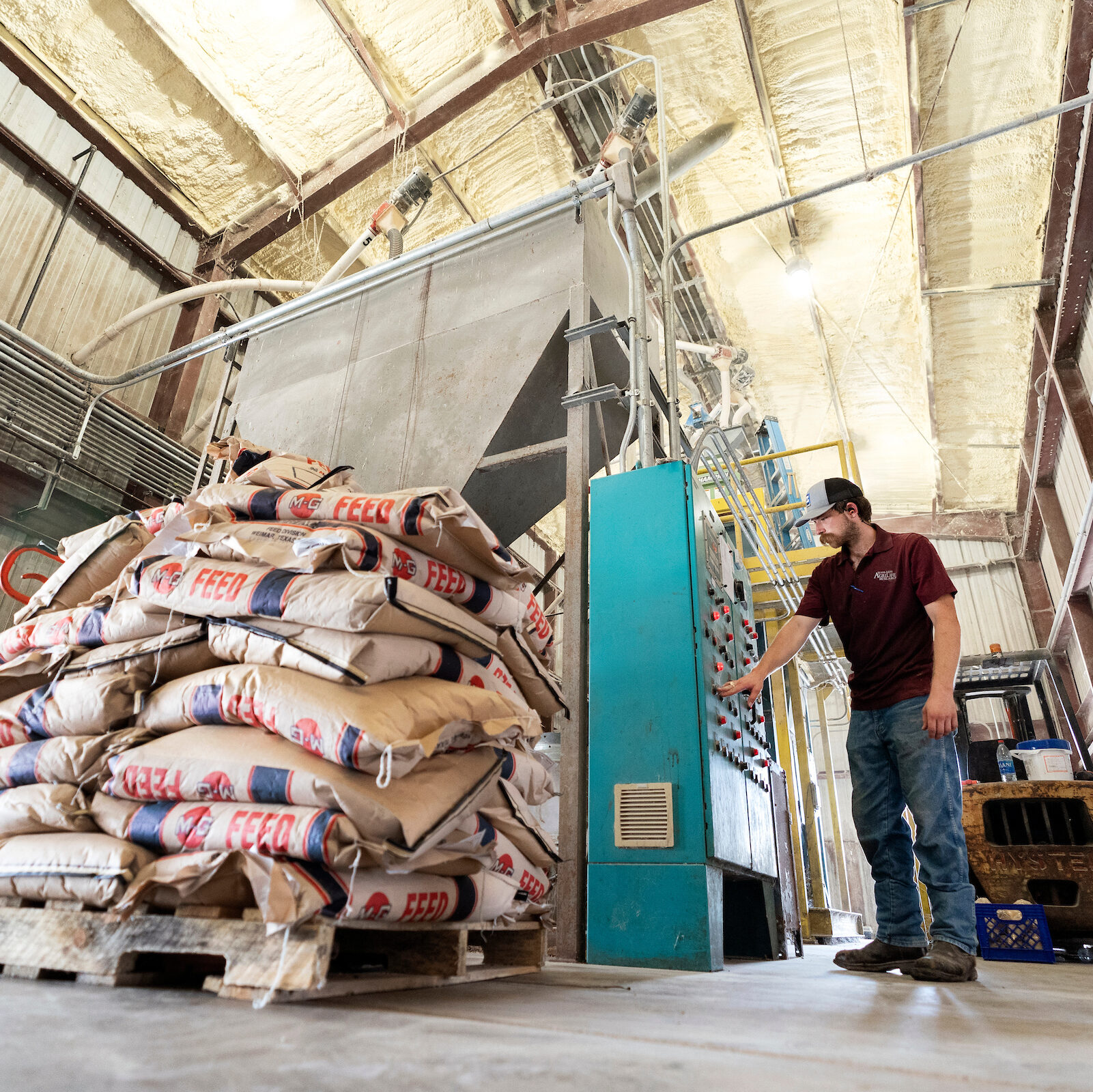 A student controlling a pallet lift filled with poultry feed